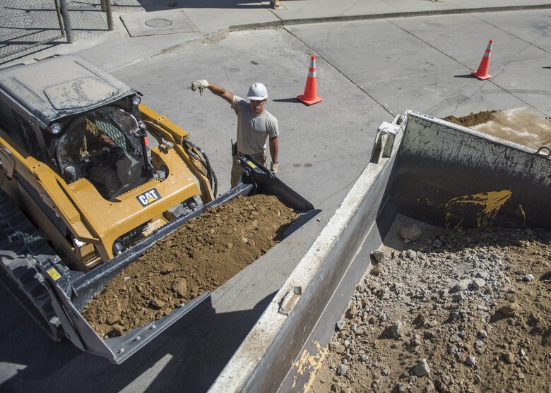 Staff Sgt. Casey Epps, 455th Expeditionary Civil Engineer Squadron pavements and equipment technician, assistant Senior Airman Bobby Rayscales Jr., 455th ECES engineer assistant, as he plows dirt, Bagram Airfield, Afghanistan, Sept. 7, 2016. The technicians worked to prepare an area for a new drainage system designed to collect excess water and precipitation. (U.S. Air Force photo by Senior Airman Justyn M. Freeman)