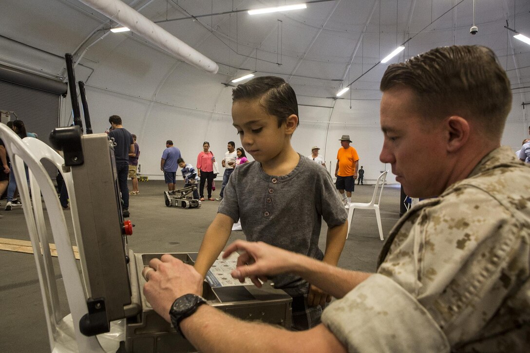 U.S. Marine Sgt. Craig Matz, an explosive ordnance disposal technician with 1st EOD Company, 7th Engineer Support Battalion, shows a Los Angeles boy how to operate an iRobot 510 Packbot during a demonstration as part of Los Angeles Fleet Week in San Pedro, Calif., Sept. 4, 2016. L.A. Fleet Week is an event designed to showcase the capabilities of the Navy-Marine Corps team to L.A. residents, and an opportunity for members of the sea services to meet and thank the community for its support. (U.S. Marine Corps photo by Sgt. Rick Hurtado)
