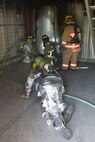 Firefighters crawl along the ground while an instructor watches during a training scenario at Scott Air Force Base, Ill., Aug. 31, 2016. The scenario was part of an instructor training course designed to test instructors in numerous ways such as their situational awareness during fire operations, looking for changes in dynamics and conditions, student behavior, operational issues and compliance with safety plans. The training featured firefighters from multiple bases and from the local community to include the 628th CES from Joint Base Charleston, South Carolina, the 19th CES from Little Rock AFB, Arkansas, the Mehlville Fire Protection District from St. Louis, Missouri, and the St. Louis Public Schools. (U.S. Air Force photo/Tech. Sgt. Jonathan Fowler)