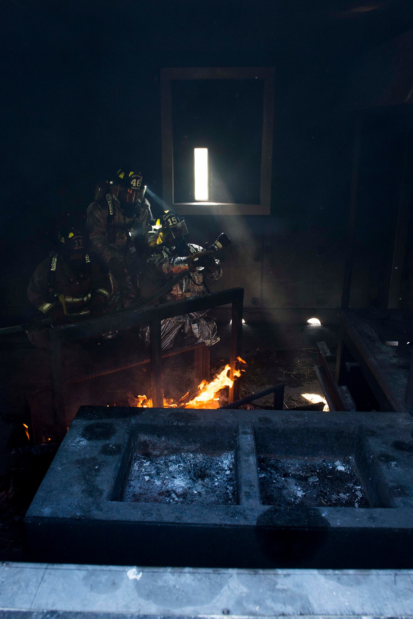 A firefighter with the 375th Civil Engineer Squadron demonstrates how he would spray a hose during a live fire training course at Scott Air Force Base, Ill., Aug. 31, 2016. The scenario was part of an instructor training course designed to test instructors in numerous ways such as their situational awareness during fire operations, looking for changes in dynamics and conditions, student behavior, operational issues and compliance with safety plans. (U.S. Air Force photo/Tech. Sgt. Jonathan Fowler)