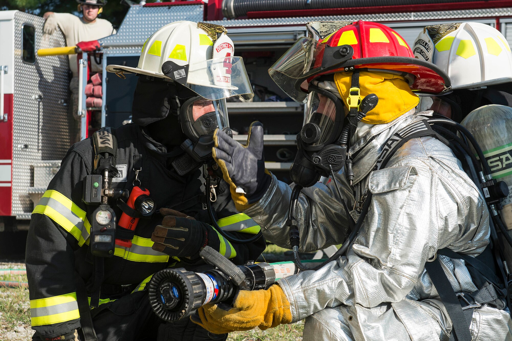 Two firefighters discuss tactics during a live fire training course at Scott Air Force Base, Ill., Aug. 31, 2016. The three-day training program explored the most recent National Fire Protection Association standards and applied principles of the standards to the student’s ability to instruct live fire training in a safe environment. (U.S. Air Force photo/Tech. Sgt. Jonathan Fowler)
