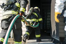 Firefighters from various organizations enter a building as part of a training scenario at Scott Air Force Base, Ill., Aug. 31, 2016. The training was part of a three-day live fire, fixed facility credentialing course developed by the International Society of Fire Service Instructors. The program explored the most recent National Fire Protection Association standards and applied principles of the standards to the student’s ability to instruct live fire training in a safe environment. (U.S. Air Force photo/Tech. Sgt. Jonathan Fowler)
