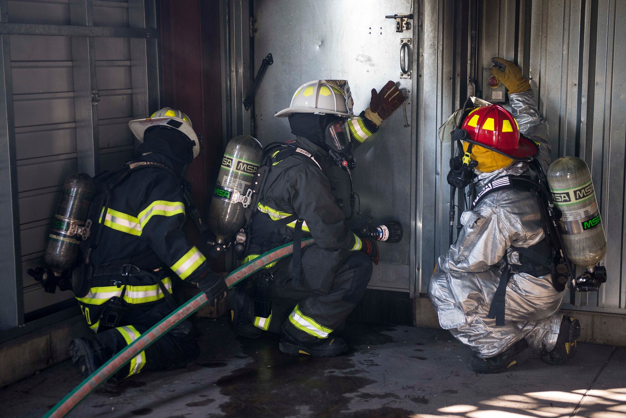 A firefighter with the 19th Civil Engineer Squadron (center) prepares to enter a room while participating in a training course at Scott Air Force Base, Ill., Aug. 31, 2016. The training was part of a three-day live fire, fixed facility credentialing course developed by the International Society of Fire Service Instructors. The program explored the most recent National Fire Protection Association standards and applied principles of the standards to the student’s ability to instruct live fire training in a safe environment. The 19th CES is located at Little Rock AFB, Arkansas. (U.S. Air Force photo/Tech. Sgt. Jonathan Fowler)