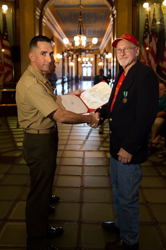 Maj. Bert J. Reinink (left), Inspector-Instructor of Company C, 1st Battalion, 24th Marines, 25th Marine Regiment, presents the Navy Commendation Medal with a bronze “V” for valor to Daniel S. Baldwin, a Marine veteran who served in Vietnam, at the State Capitol building Sept. 2, 2016. Baldwin was honored for his combat heroism during the Vietnam War and for his brave actions that helped defeat enemy forces. (U.S. Marine Corps photo by Cpl. Melissa Martens/ Released)
