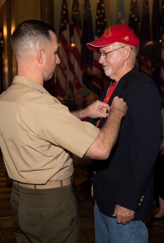 Maj. Bert J. Reinink (left), Inspector-Instructor of Company C, 1st Battalion, 24th Marines, 25th Marine Regiment, presents the Navy Commendation Medal with a bronze “V” for valor to Daniel S. Baldwin, a Marine veteran who served in Vietnam, at the State Capitol building Sept. 2, 2016. The bronze “V” is a symbol of combat heroism and recognizes individuals who have been exposed to personal hazard during participation in combat operations. Baldwin and his fellow Marines exemplified extreme bravery and fearlessness to overcome and defeat enemy forces during the Vietnam War. (U.S. Marine Corps photo by Cpl. Melissa Martens/ Released)