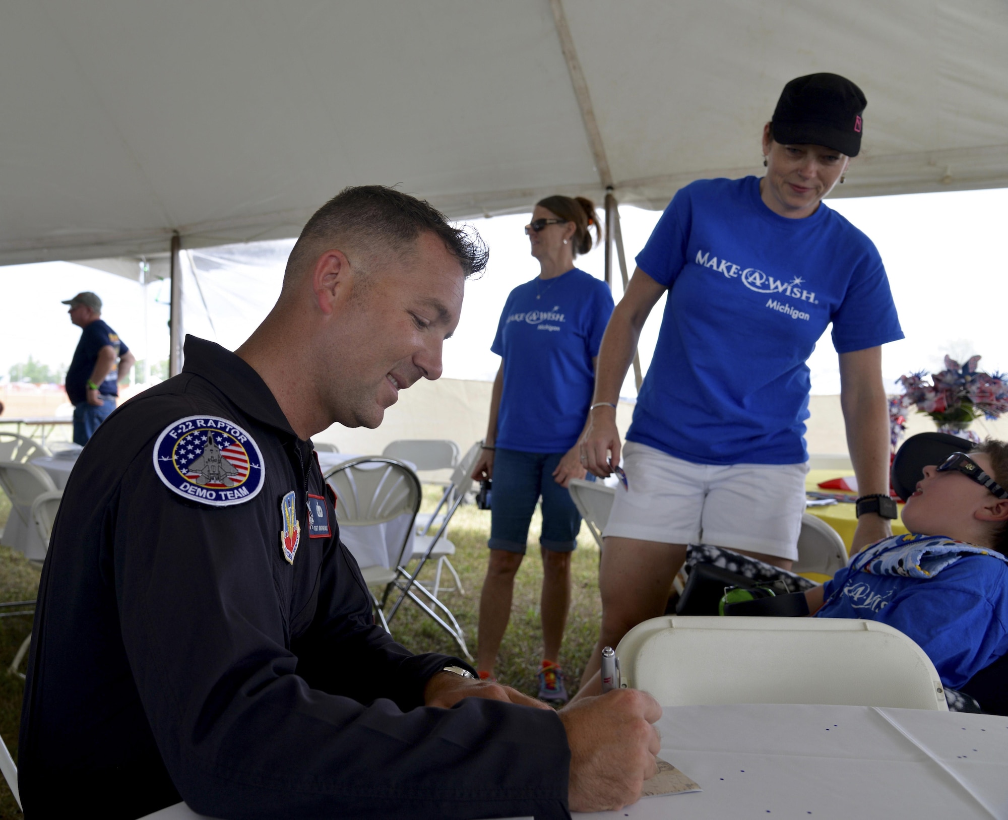 U.S. Air Force Tech. Sgt. Jonathan, F-22 Raptor Demonstration team chief, writes a special note for a Make-a-Wish Foundation recipient Aug. 20, 2016 at Willow Run Air Port in Ypsilanti, Mich.  The team spent time with the group after an F-22 rehearsal flight. (U.S. Air Force photo by 2nd Lt. Mahalia Frost)