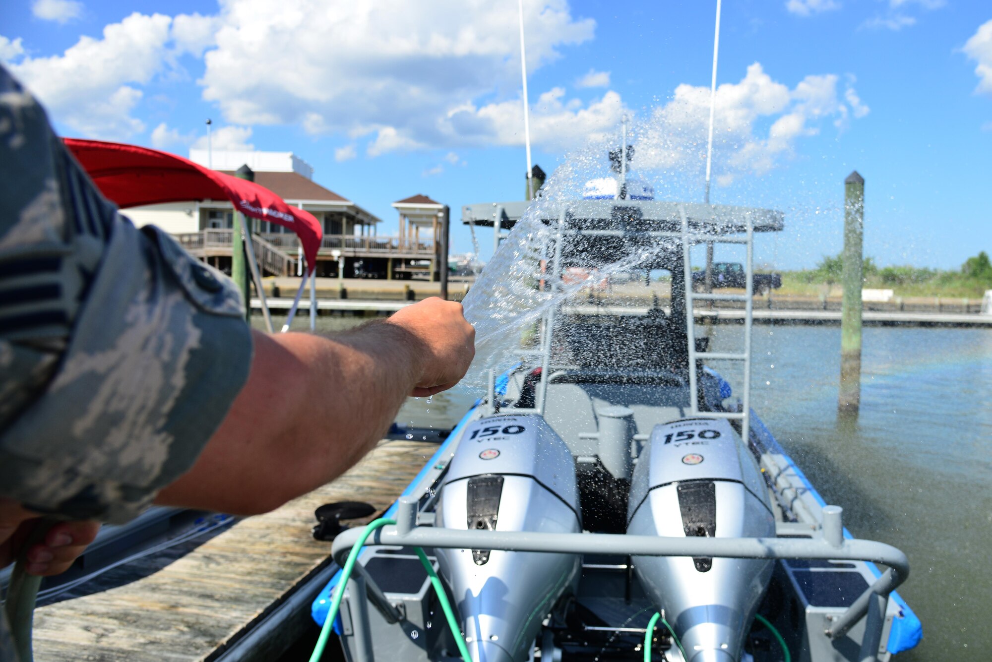 U.S. Air Force Senior Airman Philip Thompson, 633rd Security Forces Squadron boat patrolman, sprays down the boat with water after a routine patrol in the Back River, Va., Aug. 17, 2016. The boats must be cleaned after every patrol to keep the boat from rusting and working properly. (U.S. Air Force photo by Airman 1st Class Tristan Biese)
