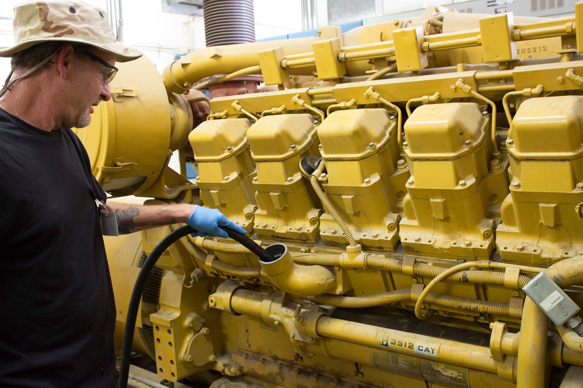 Mike Powers adds new oil to a 1000 kilowatt Caterpillar 3512 generator being serviced by his CEMIRT team based at Travis Air Force Base, California. The team recently conducted preventive maintenance on the generator to assist Edwards Air Force Base power production technicians that are currently shorthanded. (U.S. Air Force Photo/Susan Lawson)