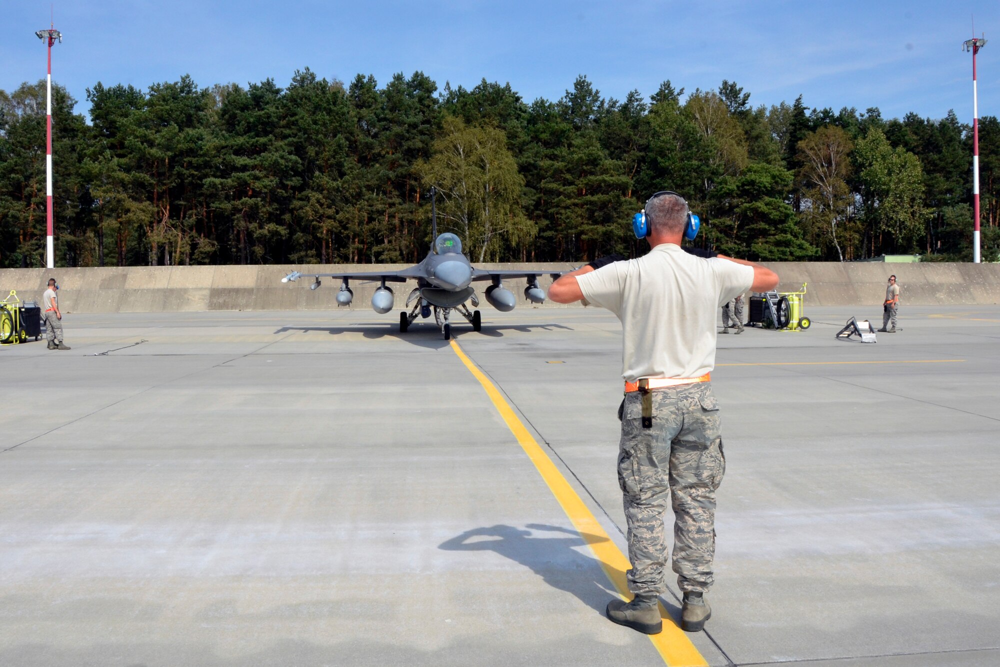 Lask Air Base, Poland -- Master Sgt. Kevin Winter, South Dakota Air National Guard 114th Aircraft Maintenance Squadron crew chief, directss an F-16 Fighting Falcon to its parking spot as it arrives here Sept. 3. More than 100 members of the 114FW are deployed in support of Aviation Detachment 16-4, a bilateral training exercise between the U.S. and Polish forces. (U.S. Air National Guard photo by Capt. Amy Rittberger/Released)