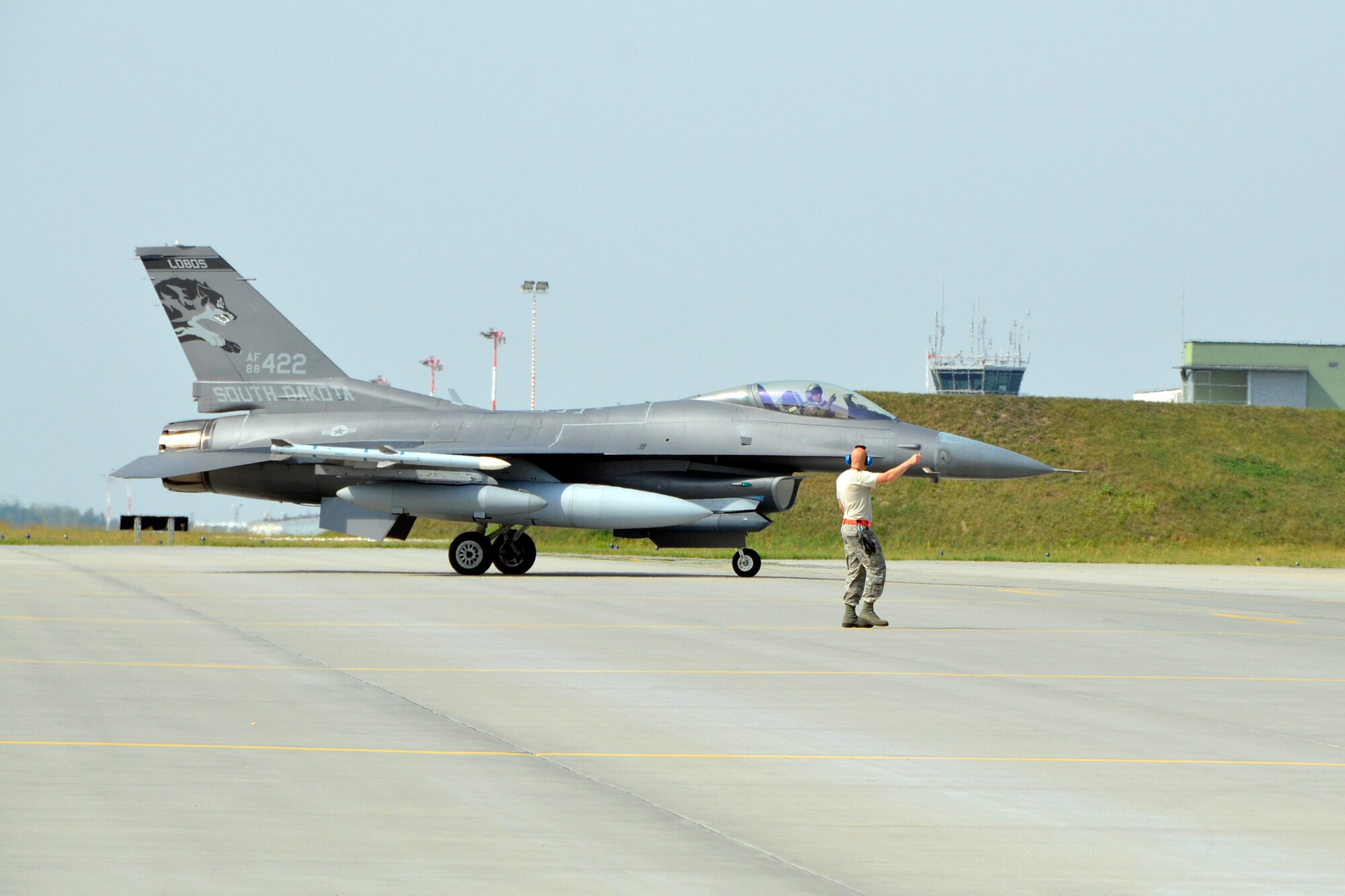 Lask Air Base, Poland - Master Sgt. Ryan Bak, South Dakota Air National Guard 114th Aircraft Maintenance Squadron crew chief, directs an F-16 Fighting Falcon to its parking spot as it arrives here Sept. 3. More than 100 members of the 114FW are deployed in support of Aviation Detachment 16-4, a bilateral training exercise between the U.S. and Polish forces. (U.S. Air National Guard photo by Capt. Amy Rittberger/Released)