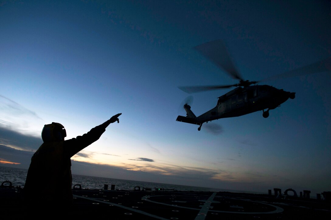 Navy Petty Officer 2nd Class Rosben Constant directs an MH-60S Seahawk helicopter from the flight deck of the USS Curtis Wilbur after a refueling in the Philippine Sea, Sept. 6, 2016. The guided-missile destroyer is supporting security and stability in the Indo-Asia-Pacific region. The helicopter is assigned to Helicopter Sea Combat Squadron 12. Navy photo by Petty Officer 3rd Class Ellen Hilkowski