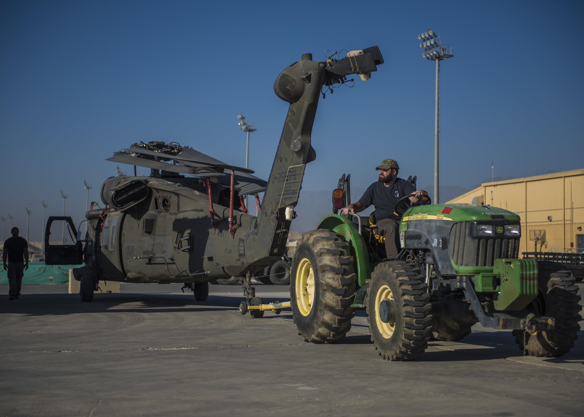 Anthony Fruge, Department of Defense contractor, uses a tractor to tow a Sikorsky UH-60 Blackhawk, Bagram Airfield, Afghanistan, Sept. 8, 2016. Airfield contractors work with aircrew members, such as loadmasters to load and unload helicopters off of aircraft when deploying and redeploying back to home stations. (U.S. Air Force photo by Senior Airman Justyn M. Freeman)