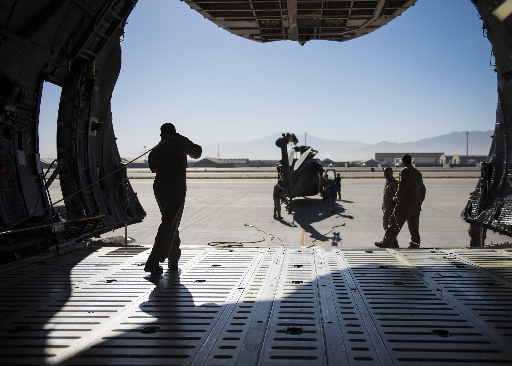 Tech. Sgt. John Crowe, 436th Airlift Wing aircraft loadmaster, pulls a tow cable towards a Sikorsky UH-60 Blackhawk, Bagram Airfield, Afghanistan, Sept. 8, 2016. An aircrew from Dover Air Force Base traveled to Bagram, to assist Army flying units pack and transport the Blackhawks back to home stations. (U.S. Air Force photo by Senior Airman Justyn M. Freeman)
