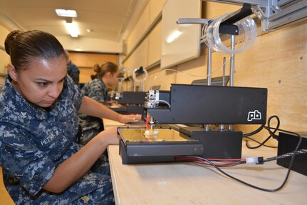 Machinery Repairman 2nd Class Lisa Petyak watches the 3-Dimensional (3-D) printer inside SERMC's Fabrication Laboratory, or Fab Lab. The Fab Lab hopes to spark creativity and problem-solving skills for Sailors assigned to SERMC. 