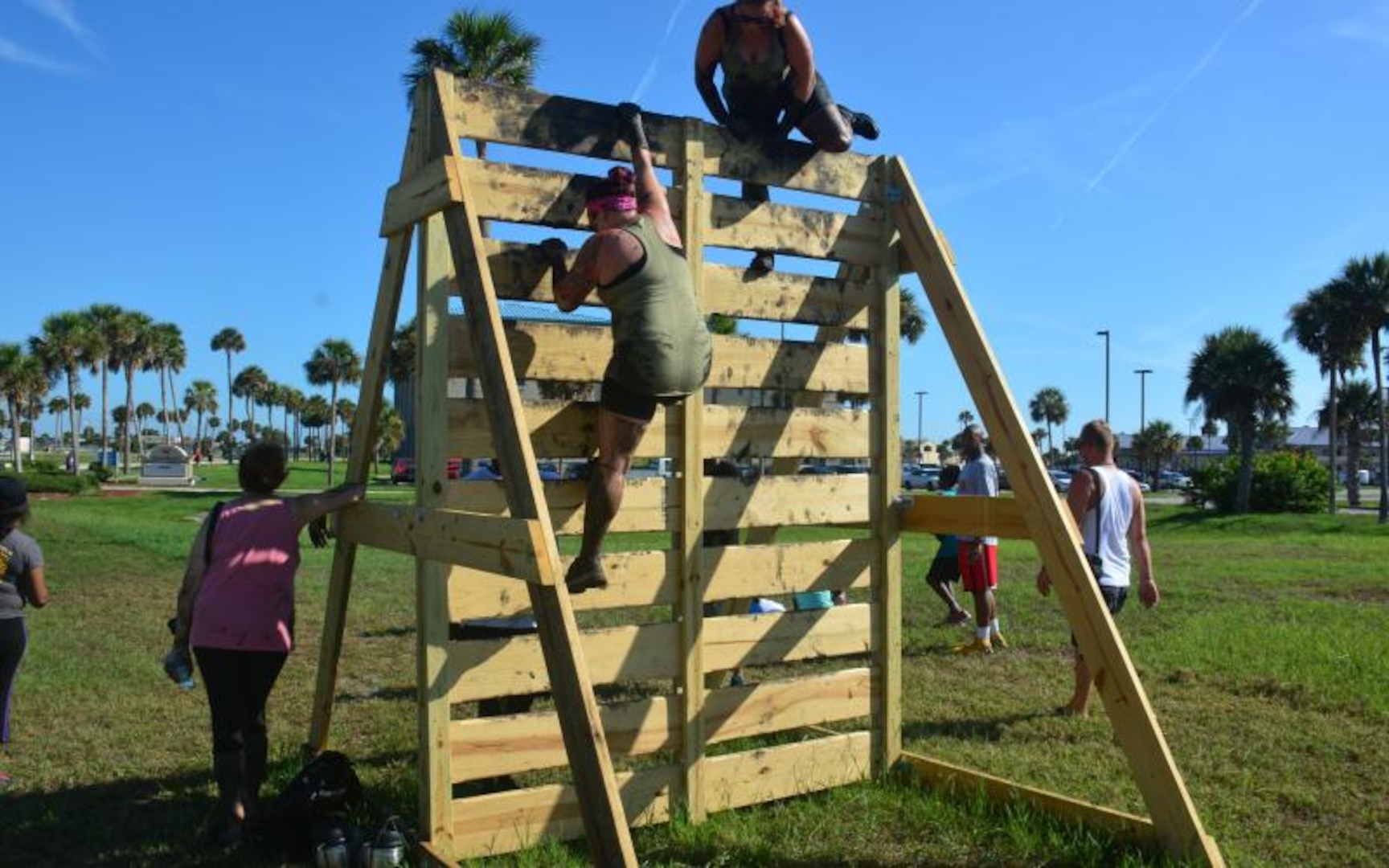 Runners climb up and over a vertical wall while participating 
in the Morale, Welfare and Recreation (MWR) 2nd Annual Mud Run. 