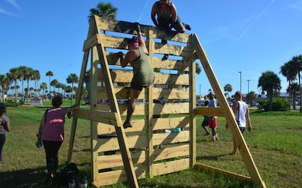 Runners climb up and over a vertical wall while participating 
in the Morale, Welfare and Recreation (MWR) 2nd Annual Mud Run. 