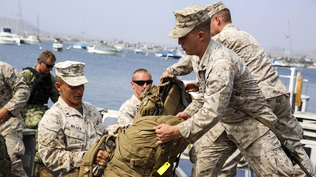 U.S. Marine Cpl. Matthew Miller, a combat engineer with Task Force Koa Moana, hands a pack to a fellow Marine after arriving in Ancon, Peru, September 2, 2016. Task Force Koa Moana is in Peru as part of a theater security cooperation engagement to integrate and improve interoperability with Peruvian Marines. Together with the USNS Pililaau, the Marines and sailors of the task force highlighted the strength and capabilities of the Navy-Marine Corps team.