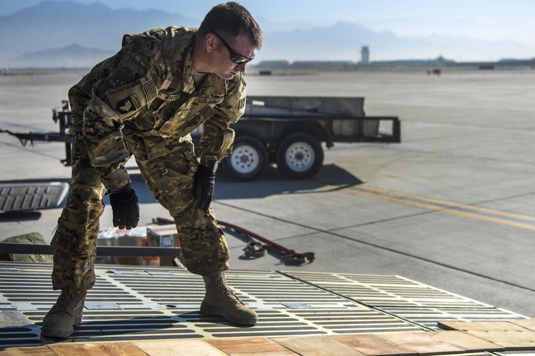 Army Chief Warrant Officer 3 Daniel White aligns wood pieces on a C-5 Galaxy at Bagram Airfield, Afghanistan, Sept. 8, 2016. White is a brigade aviation maintenance officer. The wood pieces were used to build a ramp to help upload a UH-60 Black Hawk helicopter to be transported. Air Force photo by Senior Airman Justyn M. Freeman