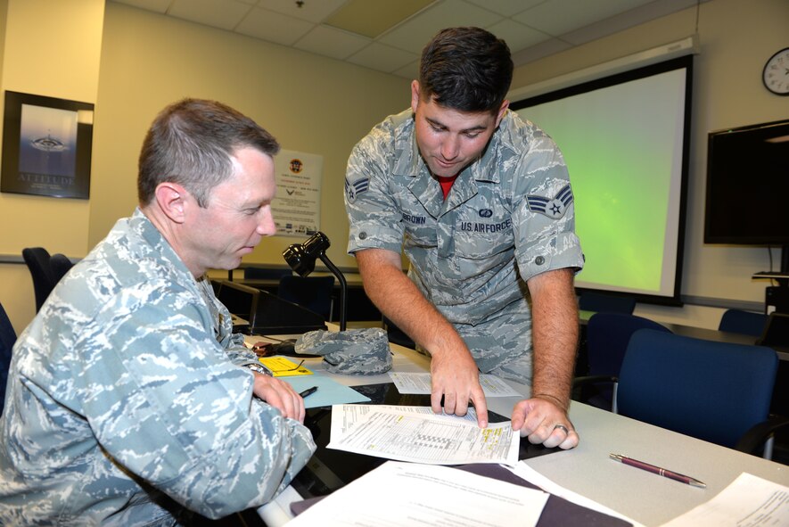 Senior Airman Matthew Brown (R), 88th Comptroller Squadron accounting technician, assists Col. Kirk Winger, the new 88th Medical Group, Aeromedical Squadron commander, with his in-bound travel orders, August 26, 2016 at Wright-Patterson Air Force Base, Ohio. Every Friday the 88th ABW Comptroller Squadron provides financial assistance with travel vouchers to new personal being assigned to Wright-Patterson AFB.  (U.S. Air Force photo / Al Bright) 