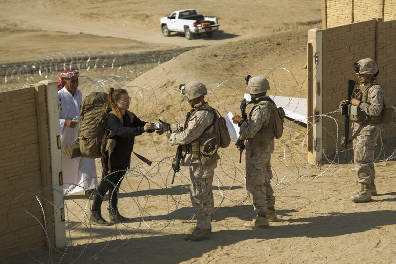 Marines with Special Purpose Marine Air Ground Task Force, Crisis Response, Central Command, check role-players ID cards before screening them during a non-combatant evacuation operation exercise at Range 220, a military operations on urbanized terrain facility, aboard the Marine Corps Air Ground Combat Center, Twentynine Palms, Calif., Aug. 24, as part of a Certification Exercise. (Official Marine Corps photo by Lance Cpl. Levi Schultz/Released)