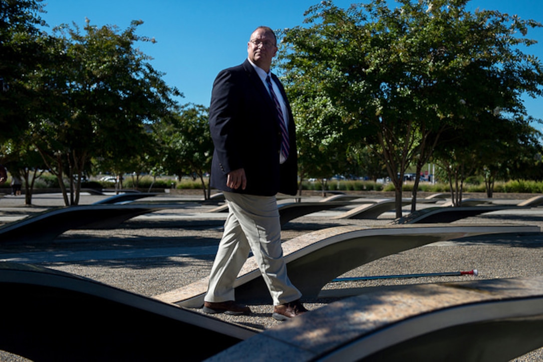 Michael Pendergrass, a retired Navy chief petty officer, looks upward toward the Pentagon while visiting the National 9/11 Pentagon Memorial Aug. 22, 2016. Pendergrass made the iconic picture of the giant American Flag being unfurled over the Pentagon’s exterior following 9/11. DoD photo by EJ Hersom