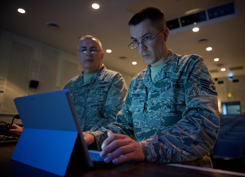 Staff Sgt. Justin Layton, 932nd Airlift Wing communication support technician, works to setup a portable WiFi connection as Col. Jonathan Philebaum, commander, 932nd AW, looks on at the Scott Air Force Base Library Auditorium, Sep. 8, 2016.  The WiFi connection will be used to support an online application during the question and answer portion of the commander's call.  (U.S. Air Force photo by Christopher Parr) 