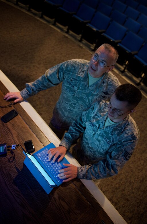 At left, Col. Jonathan Philebaum, commander of the 932nd Airlift Wing, looks up at the projected display as Staff Sgt. Justin Layton, 932nd AW communication support technician, troubleshoots getting an established connection with a portable WiFi router at the Scott Air Force Base Library Auditorium, Sep. 8, 2016.  Col. Philebaum will use an online application to interact with the audience during this commander's call Sunday of the September unit training assembly.  (U.S. Air Force photo by Christopher Parr)