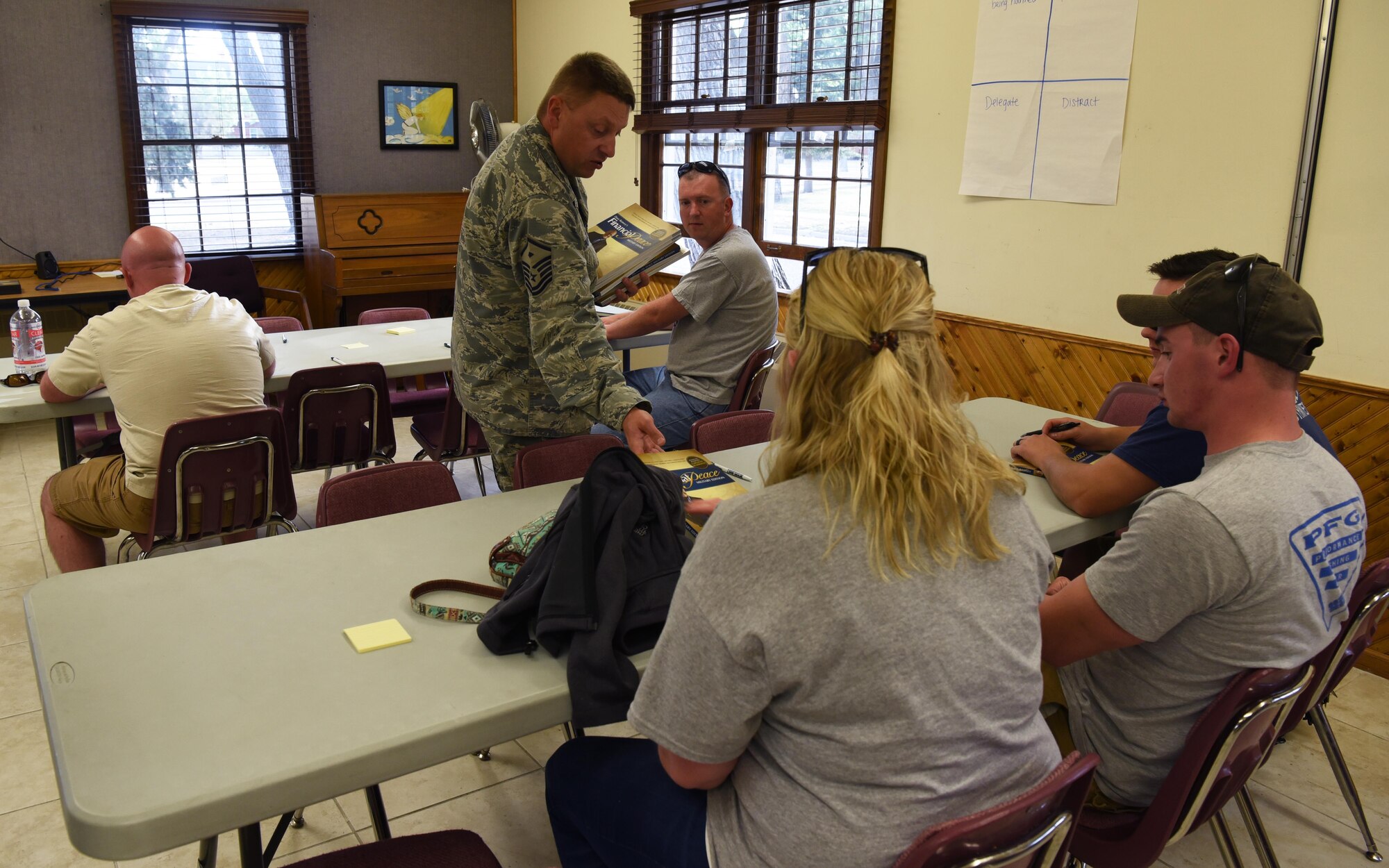 Master Sgt. Brandon Finefrock, 90th Missile Security Forces Squadron first sergeant, passes out Financial Peace University workbooks to students on F.E. Warren Air Force Base, Wyo., Sept. 7, 2016. Students followed along with a video and learned how to manage their personal finances. (U.S. Air Force photo by Airman 1st Class Breanna Carter)