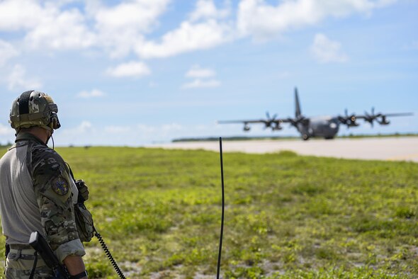 A 320th Special Tactics Squadron member controls air traffic on the Wake Island runway while a MC-130J Commando II lands during an airfield seizure exercise Aug. 24, 2016. Special Tactics Airmen jump first in order to ensure the usability of and mark the runway before providing air traffic control for follow on aircraft. (U.S. Air Force photo/Senior Airmen Stephen G. Eigel)