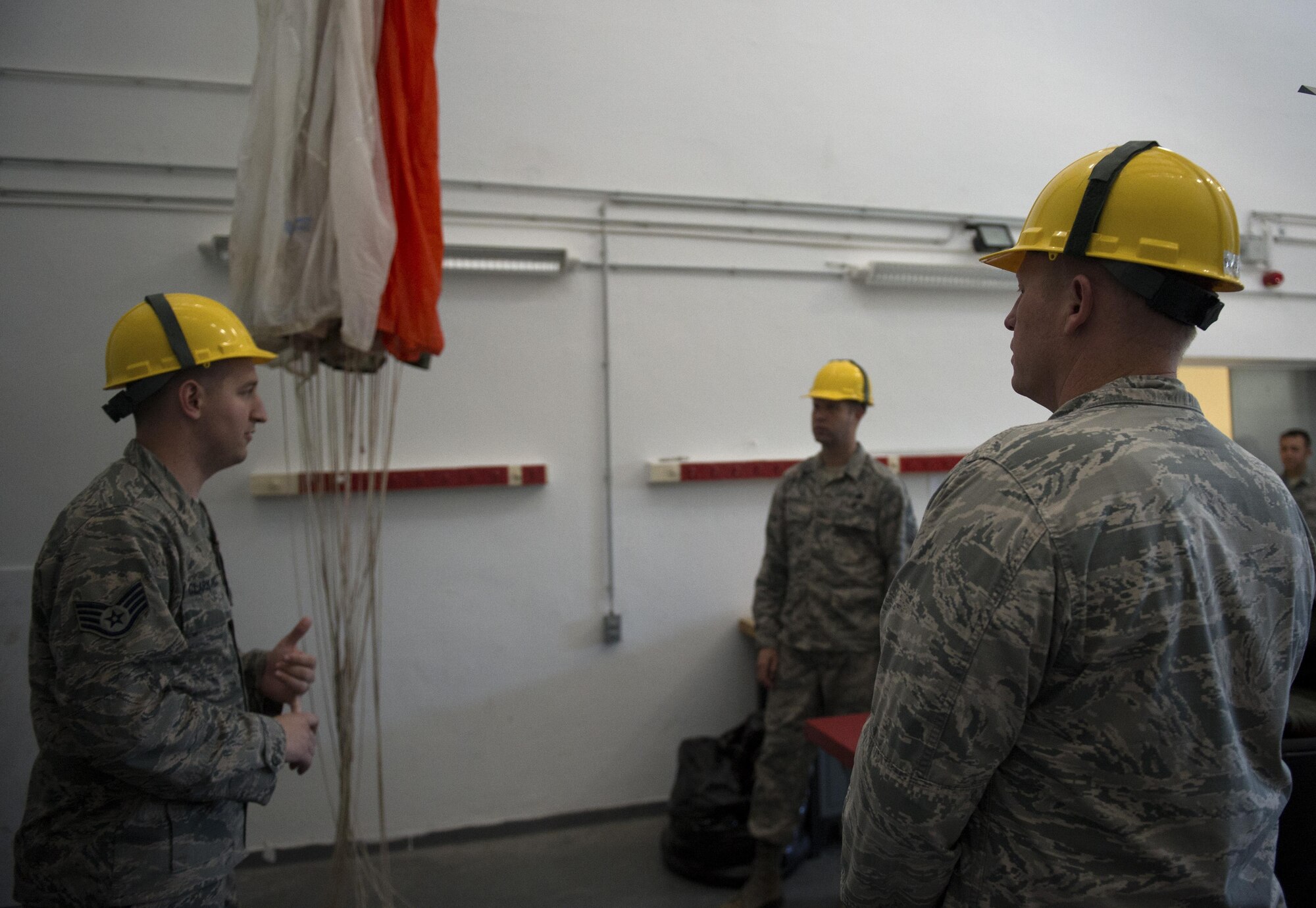 U.S. Air Force Staff Sgt. Joshua Clark-Parrick, 52nd Operations Support Squadron NCO in charge of aircrew flight operations main shop, left, speaks to Col. Joseph McFall, 52nd Fighter Wing commander, right, and Chief Master Sgt. Edwin Ludwigsen, 52nd FW command chief, center, during a Saber leadership “out and about” event at the parachute shop on Spangdahlem Air Base, Germany, Sept. 8, 2016. The event lets the 52nd FW commander and command chief get a hands on experience at Saber work centers in an effort to better understand the duties of Airmen at Spangdahlem. (U.S. Air Force photo by Airman 1st Class Preston Cherry/Released)