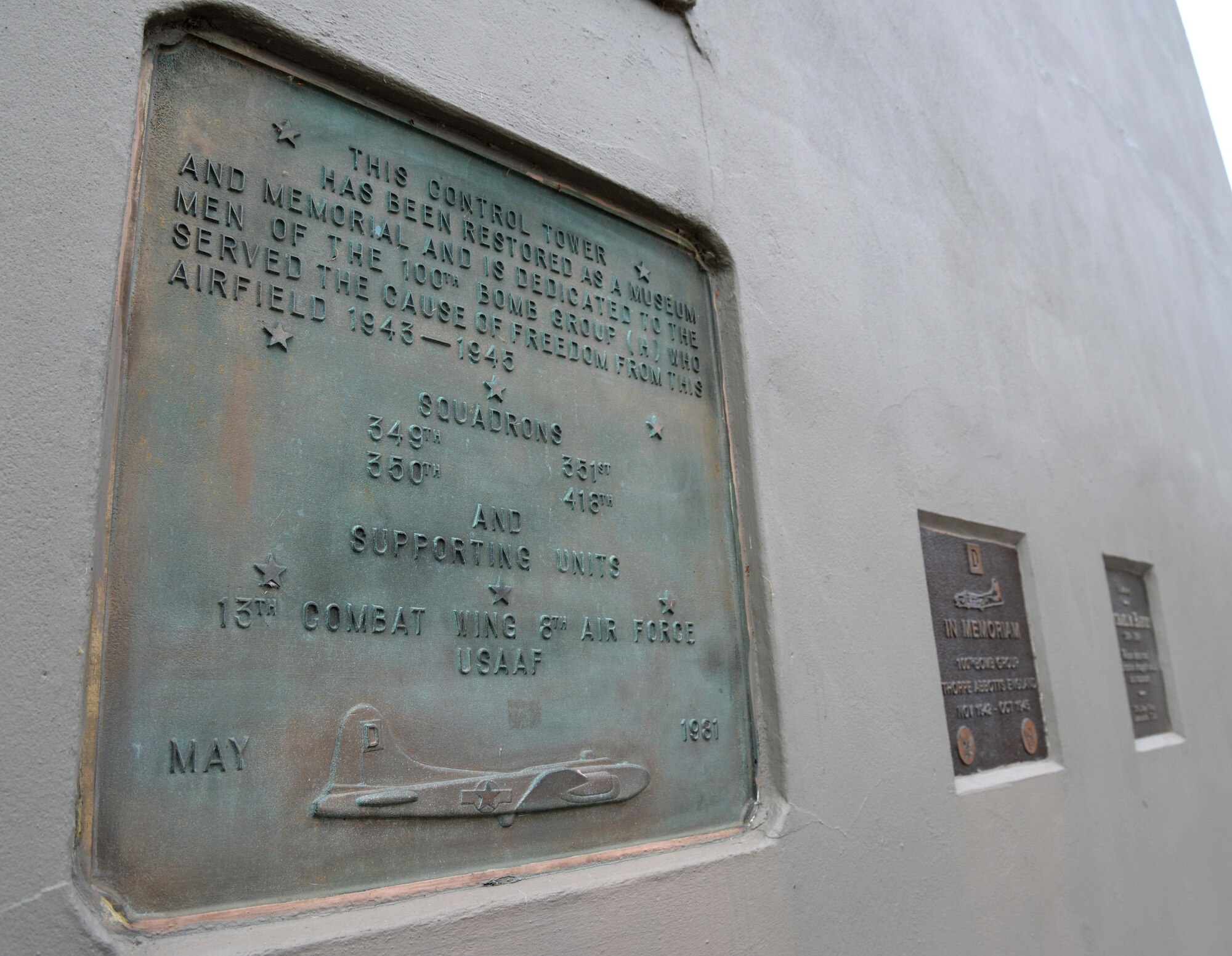 Three plaques, located near the entrance of the air traffic control tower at the 100th Bomb Group Memorial in Thorpe Abbotts, England, honor the squadrons and units which served from that airfield between 1943 to 1945. During World War II, the 100th BG suffered a tremendous loss during the initial bombing missions, which earned them the nickname, the “Bloody Hundredth.” The tower has been reconstructed from the original structure and houses donated artifacts pertaining to the memorial. (U.S. Air Force photo by Senior Airman Justine Rho) 