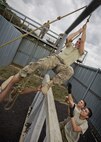 Members of the 91st Security Forces Group swing an Airman through an obstacle at Camp Grafton Training Center, N.D., Sept. 7, 2016. The goal of the obstacle is to move the team through the metal bars, without touching wooden supports, using only a rope. (U.S. Air Force photo/Airman 1st Class J.T. Armstrong)