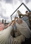 Members of the 91st Security Forces Group swing an Airman through an obstacle at Camp Grafton Training Center, N.D., Sept. 7, 2016. The goal of the obstacle is to move the team through the metal bars, without touching wooden supports, using only a rope. (U.S. Air Force photo/Airman 1st Class J.T. Armstrong)