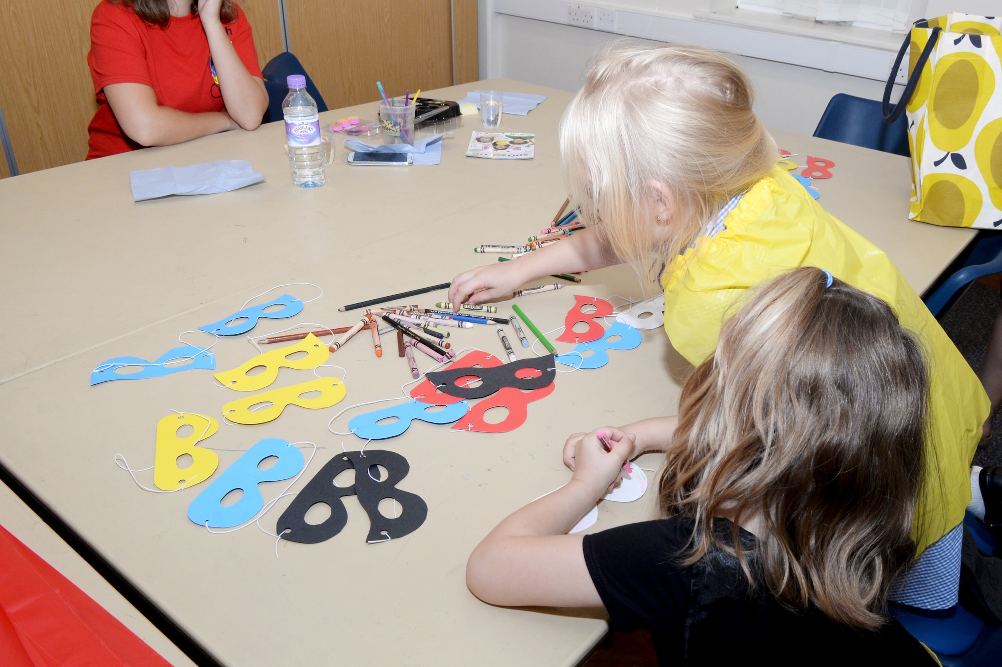 Children decorate super hero masks during the Hearts Apart dinner Sept. 8, 2016, on RAF Mildenhall. The monthly Hearts Apart dinners are a way for spouses and family members of deployed Airmen to gather together and connect. This Hearts Apart theme was “super heroes.” (U.S. Air Force photo by Airman 1st Class Tenley Long)