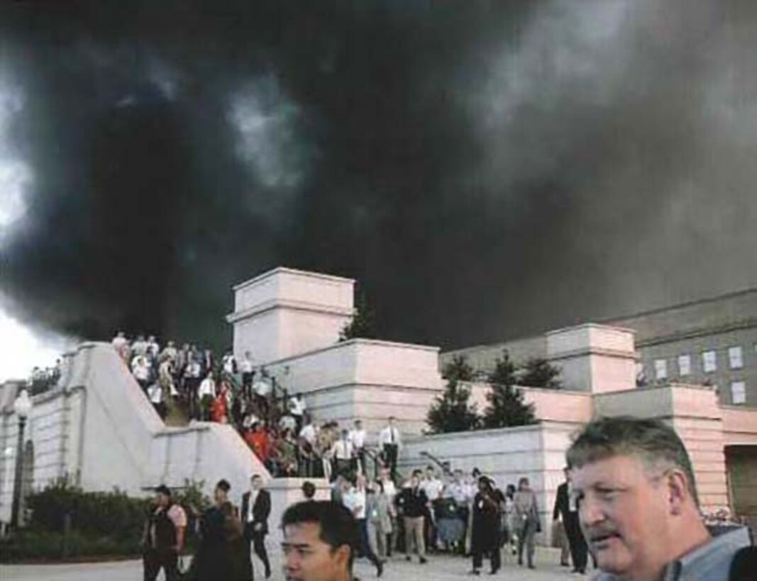 With smoke from the fires raging in Corridors 4 and 5 overhead, Pentagon personnel evacuate via the Corridor 2 exit to the south parking lot, Sept. 11, 2001. Navy photo