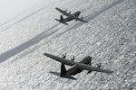 A flight of two C-130 Hercules aircraft from the Georgia Air National Guard's 165th Airlift Wing bank right while flying to a drop zone under fighter aircraft escort during exercise Sentry Aloha at Joint Base Pearl Harbor-Hickam, Hawaii. Sentry Aloha focuses on integration of fighter and support aircraft in a simulated combat setting. (U.S. Air National Guard photo by Airman 1st Class Stan Pak)