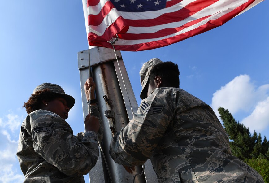 From left, Airman 1st Class Bria Jackson, 786th Civil Engineer Squadron emergency management specialist, and Senior Airman Daneeka Mucker, 86th Logistic Readiness Squadron hazmart pharmacy specialist, lower the American flag during a 9/11 Memorial Retreat Ceremony Sept. 9, 2016 at Ramstein Air Base Germany. On Sept. 11, 2001, 19 hijackers overtook four commercial airliners, crashing two into the World Trade Center towers in New York City, New York. (U.S. Air Force photo/Senior Airman Tryphena Mayhugh) 