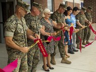Marines and the Ouellette family cut the ribbon with golden scissors in front of the new headqaurters building at Camp Geiger on Marine Corps Installation East – Marine Corps Base Camp Lejeune Aug. 31. The hall is dedicated to Cpl. Michael W. Ouellette, recifpient of the Navy Cross, for his actions during a combat patrol in the Now Zad district where an improvised explosive devise left him critically wounded.