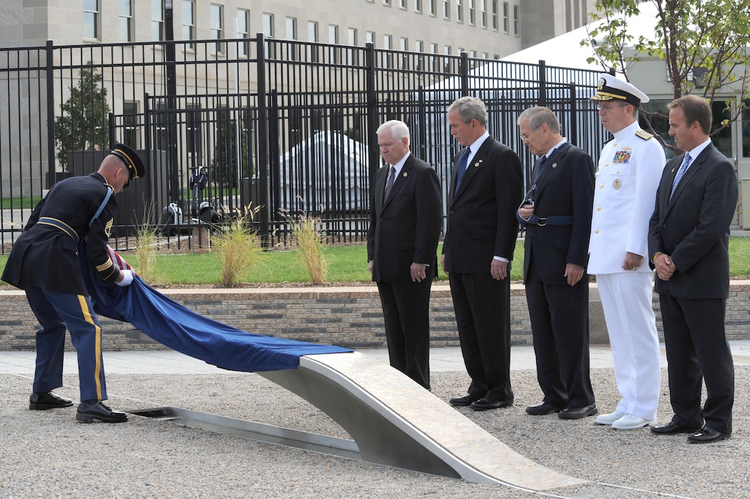 Army Sgt. 1st Class Peter George Lentz unveils the first bench at the Pentagon 9/11 Memorial as Defense Secretary Robert Gates; President George W. Bush; Donald Rumsfeld, former defense secretary; Navy Adm. Michael Mullen, the chairman of the Joint Chiefs of Staff; and James F. Laychak, chair of the Pentagon Memorial Fund, look on, Sept. 11, 2008. The site contains 184 inscribed memorial units honoring the 59 people aboard American Airlines Flight 77 and the 125 in the building who lost their lives that day. DoD photo by Cherie Cullen