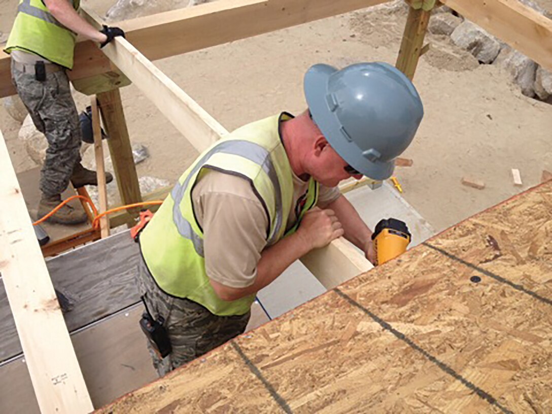 Senior Master Sgt. Charles Crawford uses a nail gun to install rafters for the roof of the wrap-around porch on the multi-use building 445th Civil Engineer Squadron Airmen helped construct at Camp William Hinds in Maine. The project is part of the Innovative Readiness Training program, a Department of Defense initiative. (U.S. Air Force photo/Master Sgt. David Merlo)