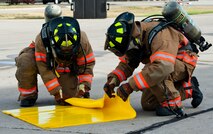 Firefighters with the 5th Civil Engineer Squadron roll up a spill absorbent pad during a fuel spill exercise at Minot Air Force Base, N.D., Sept. 8, 2016. The yellow pads are used to stop the fuel spill immediately while the firefighters use blue pads to absorb the liquid, which was part of the annual training the firefighters received. (U.S. Air Force photo/Airman 1st Class Jonathan McElderry)