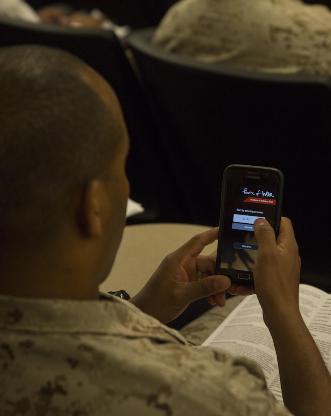A Marine downloads the Theater of War Mobile App during a reading of “Ajax” by Theater of War at Marine Corps Support Facility New Orleans, Sept. 9, 2016. The application allows audience members to give live feedback about the performance. The purpose of Theater of War is to engage military audiences in a discussion of behavioral health and suicide prevention through a dramatic reading of Sophocles’ classic play. (U.S. Marine Corps photo by Sgt. Ian Leones/Released)