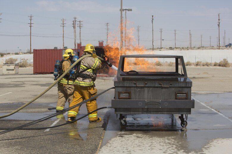 Combat Center firefighters extinguish a simulated car fire at the Fire Department aboard Marine Corps Air Ground Combat Center, Twentynine Palms, Calif., Aug. 26, 2016. (Official Marine Corps photo by Cpl. Thomas Mudd/Released)
