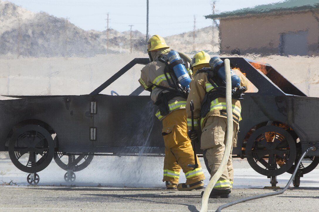 Combat Center firefighters extinguish a simulated care fire at the Fire Department aboard Marine Corps Air Ground Combat Center, Twentynine Palms, Calif., Aug. 26, 2016. (Official Marine Corps photo by Cpl. Thomas Mudd/Released)