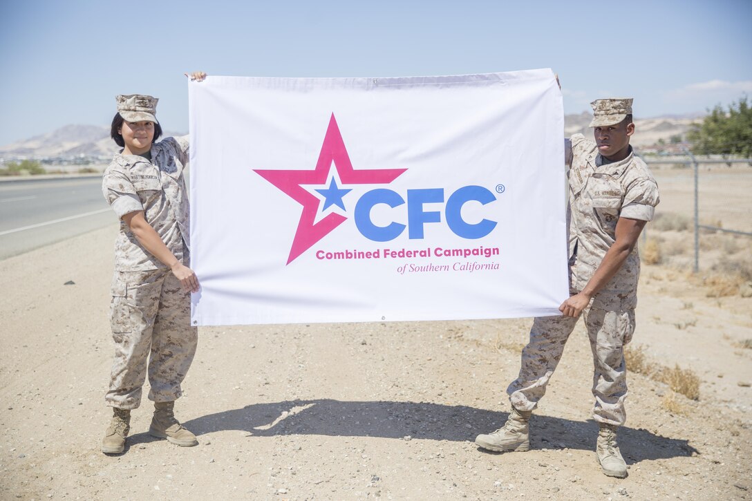 Lance Cpl. Dantre Strobridge and Lance Cpl. Deisy Martinez, postal clerks, Headquarters Battalion, hang the Combined Federal Campaign banner at the main gate aboard the Marine Corps Air Ground Combat Center, Twentynine Palms, Calif., Aug. 29, 2016. (Official Marine Corps photo by Lance Cpl. Dave Flores/Released)