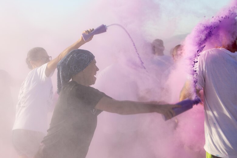 A spouse of a Marine with 1st Battalion, 7th Marine Regiment, throws colored cornstarch on runners during a battalion-wide 5k color run aboard Marine Corps Air Ground Combat Center, Twentynine Palms, Calif., Sept. 2, 2016. (Official Marine Corps photo by Cpl. Levi Schultz/Released)