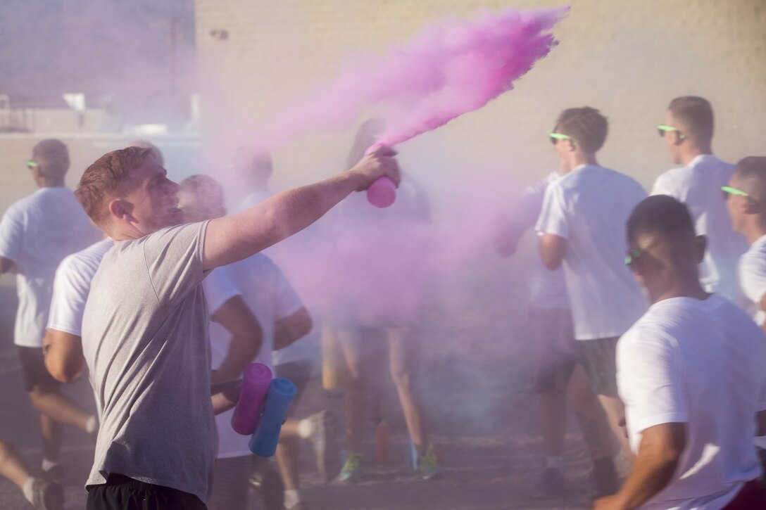 A Marine with 1st Battalion, 7th Marine Regiment, throws colored cornstarch on runners during the battalion-wide 5k color run aboard Marine Corps Air Ground Combat Center, Twentynine Palms, Calif., Sept. 2, 2016. (Official Marine Corps photo by Cpl. Levi Schultz/Released)