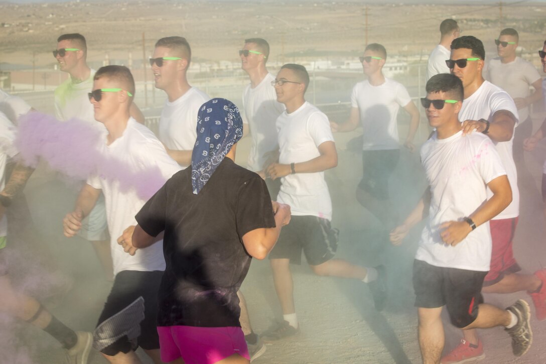 A spouse of a Marine with 1st Battalion, 7th Marine Regiment, throws colored cornstarch on runners during a battalion-wide 5k color run aboard Marine Corps Air Ground Combat Center, Twentynine Palms, Calif., Sept. 2, 2016. (Official Marine Corps photo by Cpl. Levi Schultz/Released)