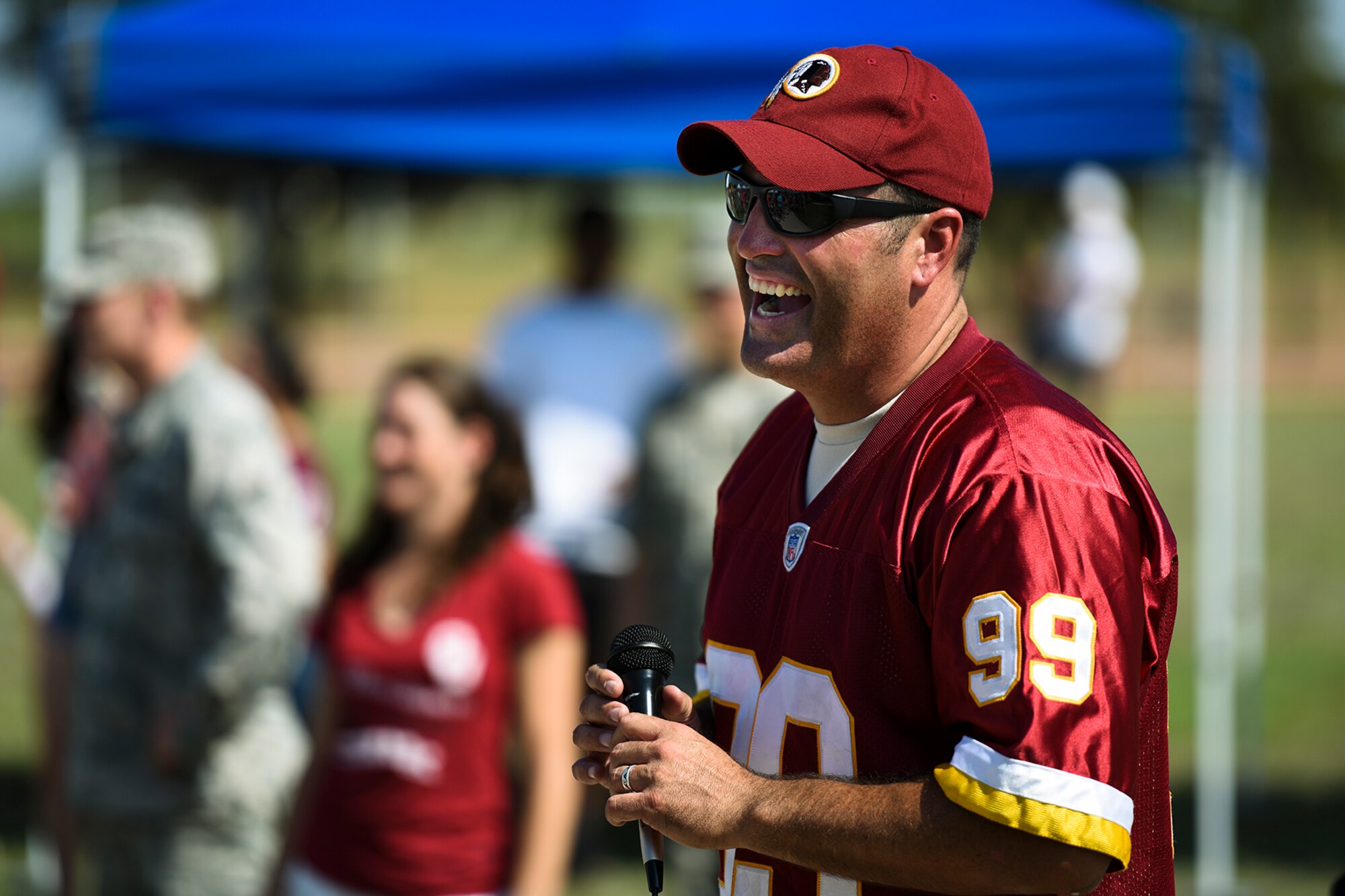 U.S. Air Force Master Sgt. Blake Ferguson, 17th Force Support Squadron airman leadership school commandant, laughs after speaking to the attendees of the Combined Federal Campaign kickoff tailgate party at the parade field on Goodfellow Air Force Base, Texas, Sept. 8, 2016. Ferguson spoke about the CFC and encouraged Goodfellow members to participate in the campaign. (U.S. Air Force photo by Senior Airman Devin Boyer/Released)