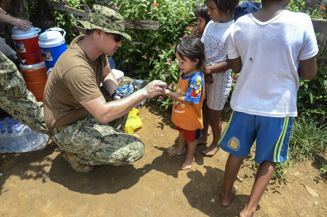Navy Petty Officer 3rd Class Anthony Salazar hands out treats to children in Cartagena, Colombia, Sept. 8, 2016. Salazar, a hospital corsman, is in Colombia with a team building a latrine for the Cabildo Indigena Zenu community during Southern Partnership Station 2016. The effort fosters a lasting relationship with the people of Central and South America through exercises, operations and community projects. Navy photo by Petty Officer 1st Class Kimberly Clifford